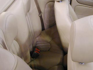 IMAGE: A very expensive leather-furnished Jaguar convertible, showing its driver seat pressing tightly against the small back seats.