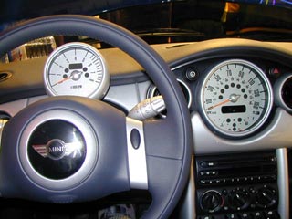IMAGE: View from the driver's perspective in a BMW Mini, showing the tachometer in the driver's line of sight, and the speedometer lowered and in the center console.